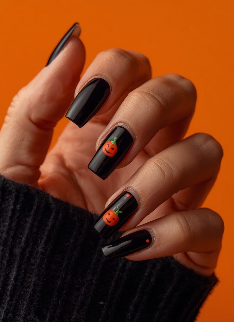 Black Halloween nails with cute pumpkin nail art and glossy spooky manicure design on orange background