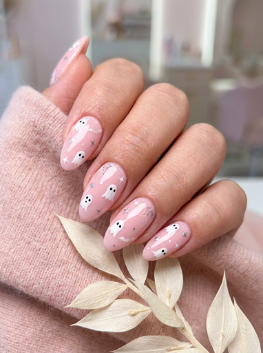 Cute pink Halloween ghost nail art on almond shaped nails with tiny white ghost designs and stars, perfect simple Halloween manicure idea