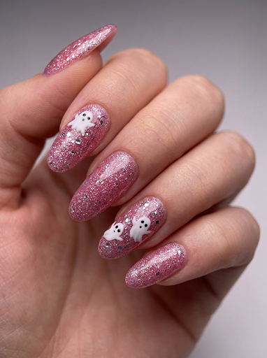 Pink glitter Halloween nails with cute white ghost designs on almond shaped nails, perfect spooky season manicure idea